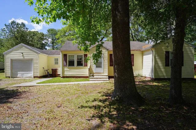 a front view of a house with a garden and trees