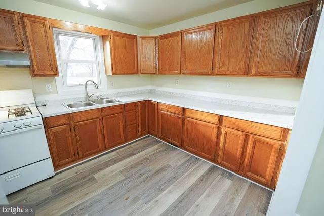 an empty room with wooden floor cabinet and windows