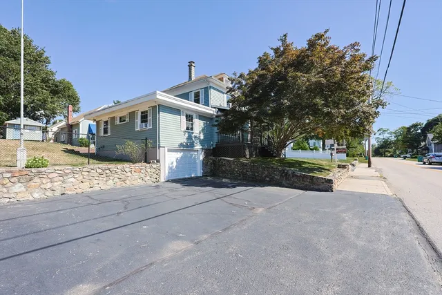 a view of a house with a yard and large tree