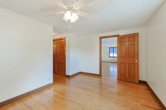 an empty room with wooden floor closet and windows
