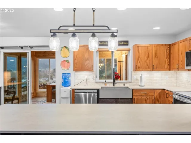 a kitchen with stainless steel appliances kitchen island wooden cabinets and a large window