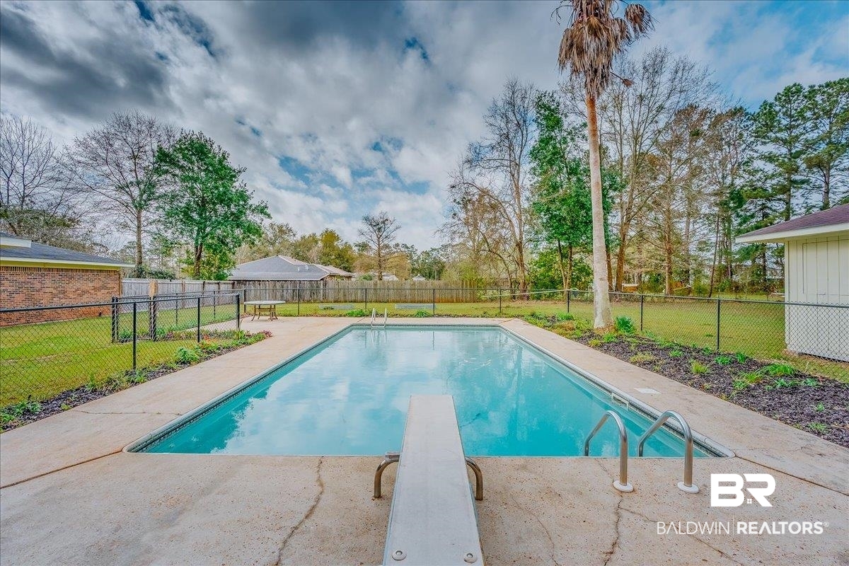 440 Dykes Road Mobile, AL 36608 - Photo 31 of 49 View of swimming pool featuring a fenced in pool, a lawn, a fenced backyard, and a diving board
