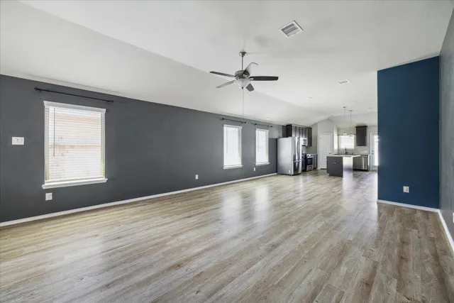 a view of an empty room with window and wooden floor