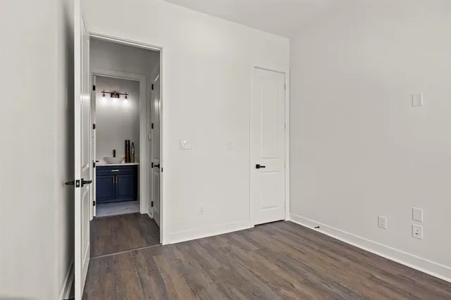 a view of a hallway with wooden floor and a bathroom