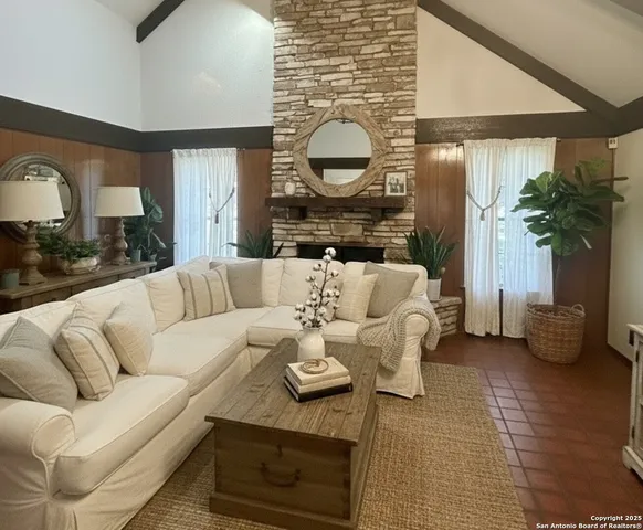 a living room with furniture a fireplace and potted plants