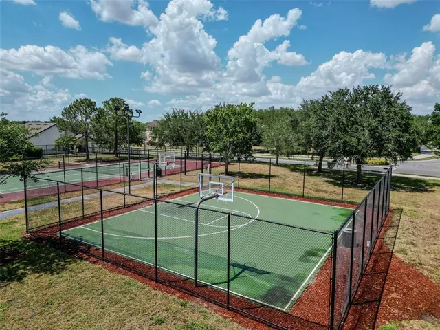 a view of a tennis ground with large trees