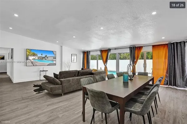 a living room with furniture a large window and dining table