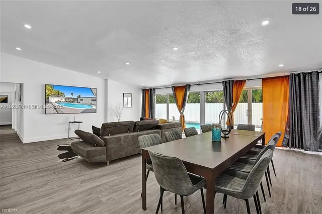 a living room with furniture a large window and dining table