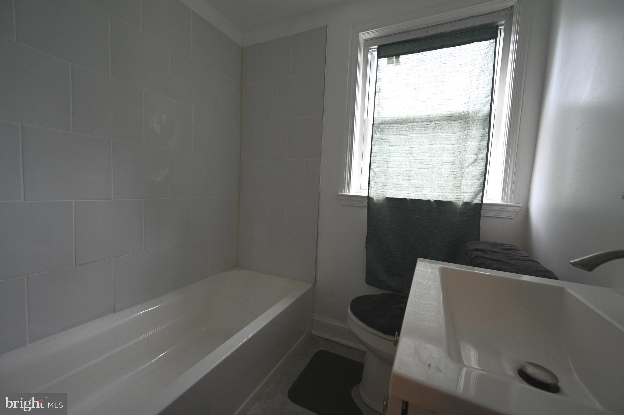 2458 Nevada Street Baltimore, MD 21230 - Photo 11 of 19 a bathroom with a bathtub a window and a shower