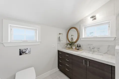 a bathroom with a toilet sink vanity and mirror