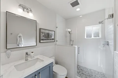 a bathroom with a toilet a sink a mirror a vanity and shower