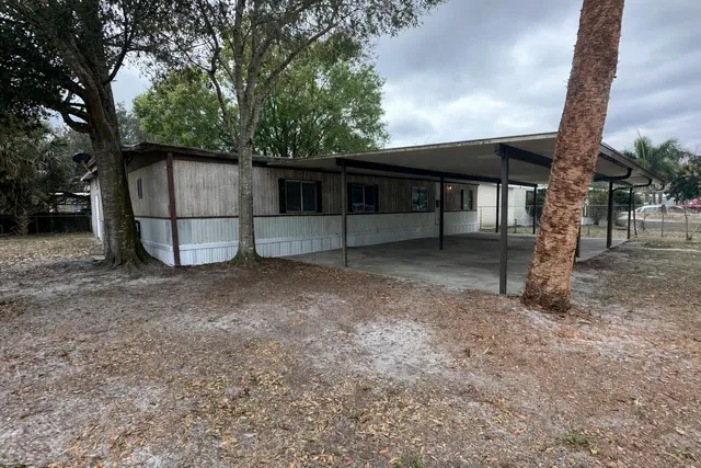 a view of backyard with large tree and wooden fence