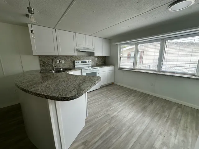 a kitchen with kitchen island granite countertop a sink cabinets and wooden floor
