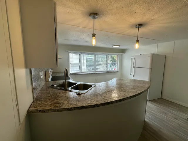 a kitchen with stainless steel appliances granite countertop a sink a refrigerator and a granite counter tops