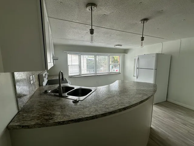 a kitchen with granite countertop a sink a counter top space and cabinets