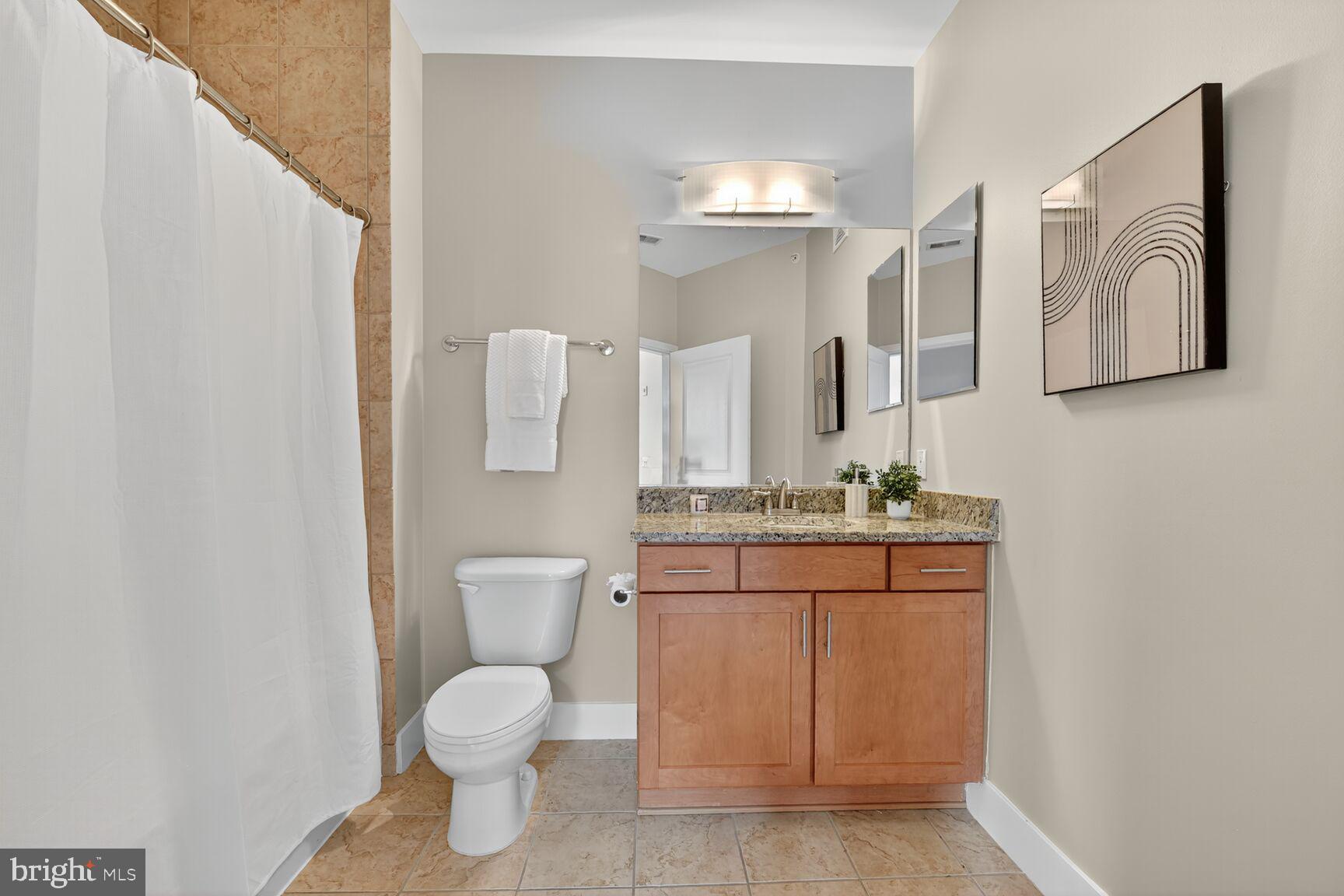 1800 Wilson Boulevard, Unit 449 Arlington, VA 22201 - Photo 55 of 99 a bathroom with a granite countertop toilet sink and mirror