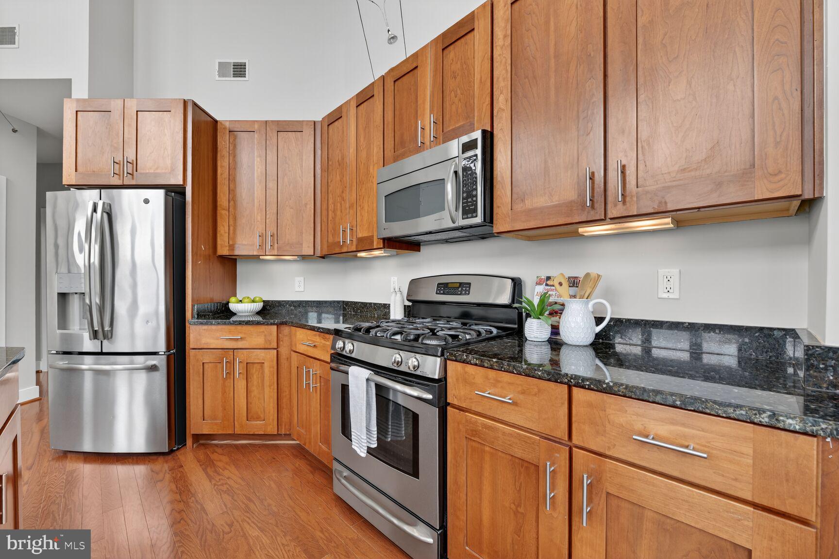 1800 Wilson Boulevard, Unit 449 Arlington, VA 22201 - Photo 10 of 99 a kitchen with stainless steel appliances granite countertop a refrigerator stove top oven and sink with wooden floor