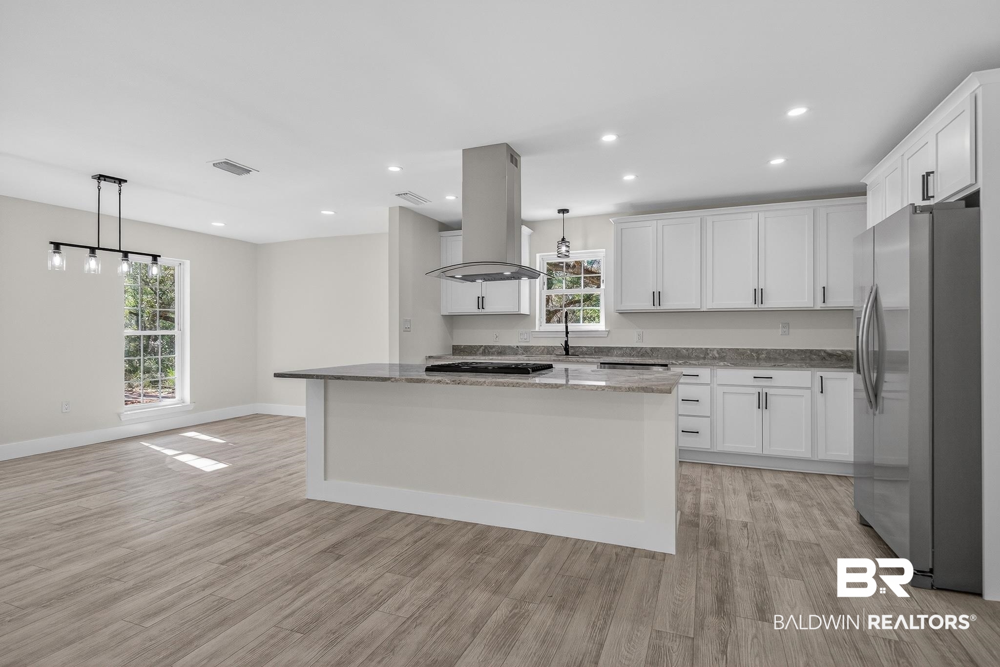 10650 Old Pascagoula Road Theodore, AL 36582 - Photo 34 of 77 Kitchen with decorative light fixtures, a kitchen island, light stone counters, stainless steel fridge, and white cabinetry