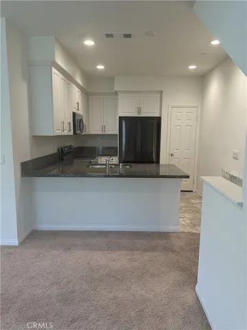 a large kitchen with a sink stainless steel appliances and cabinets