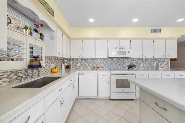 a kitchen with granite countertop white cabinets and white appliances