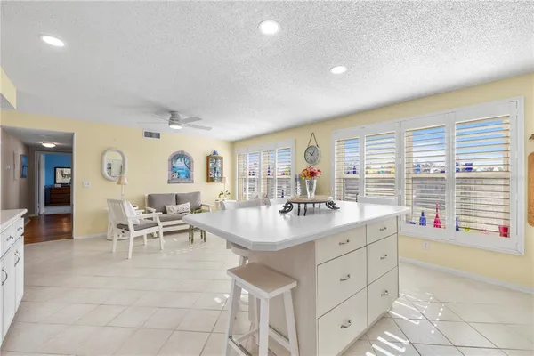 a very nice looking dining room with kitchen island granite countertop a large window and white cabinets