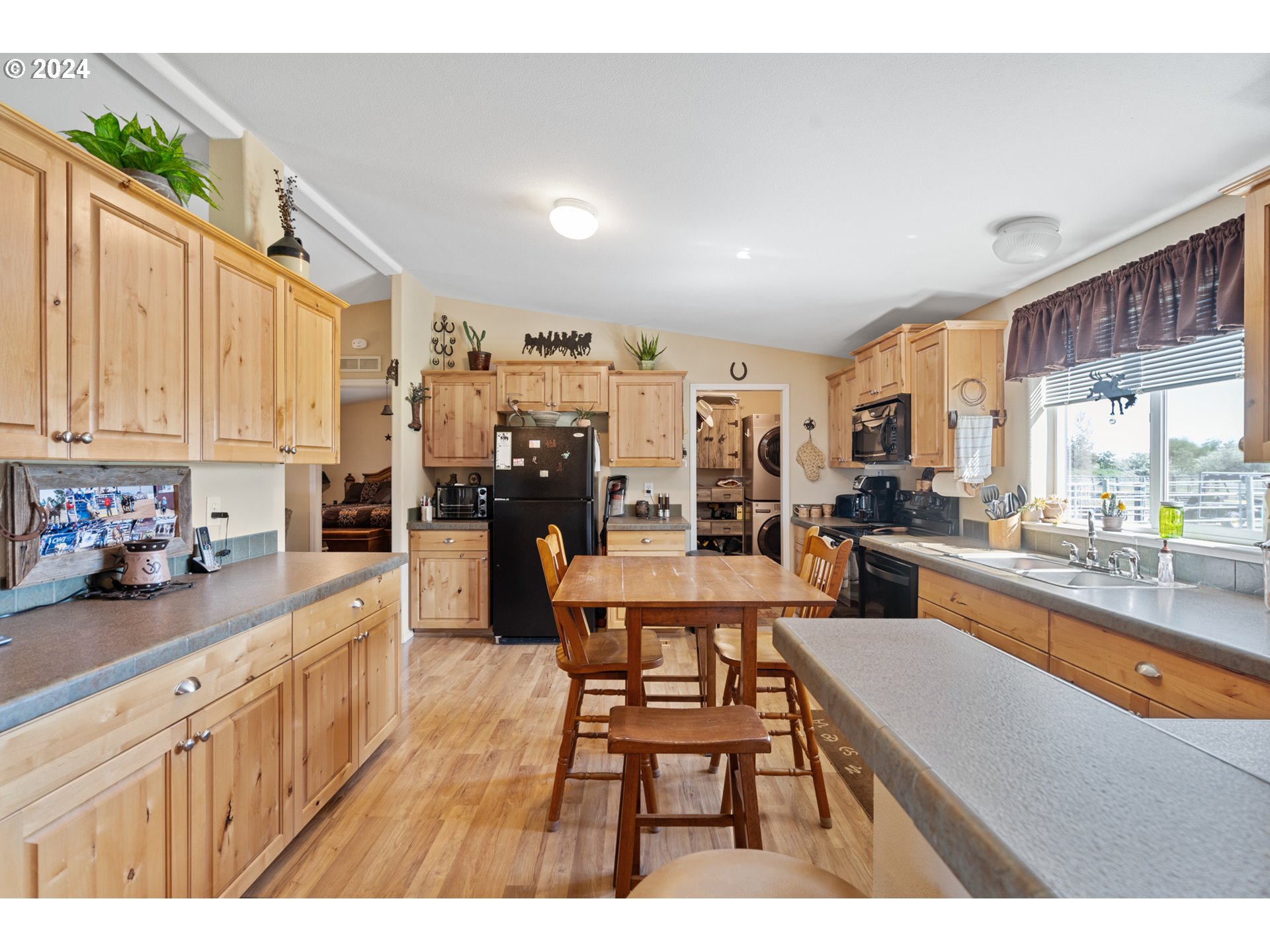 81385 North Golda Road Hermiston, OR 97838 - Photo 10 of 40 a open kitchen with stainless steel appliances kitchen island granite countertop a refrigerator a stove a sink dishwasher and white cabinets with wooden floor