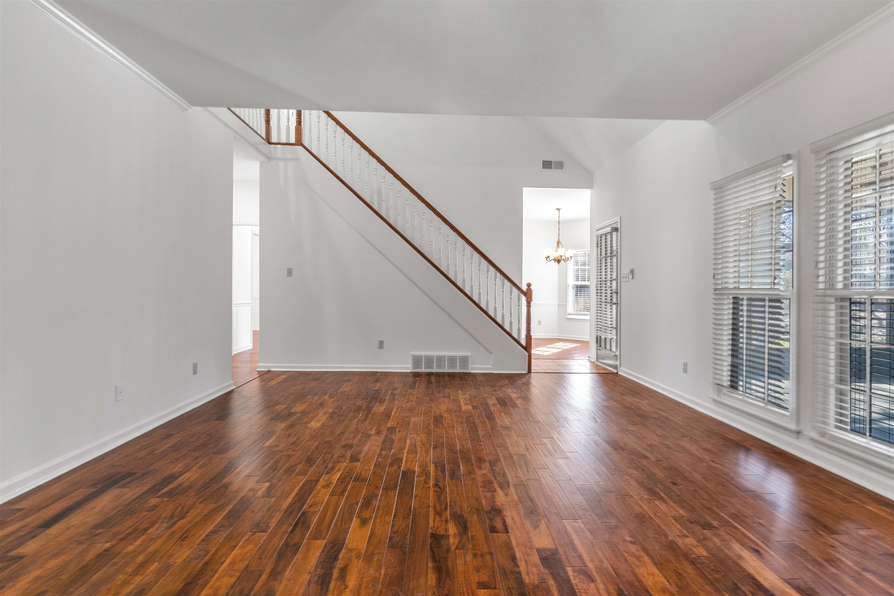 Unfurnished living room with dark wood-style floors and a chandelier