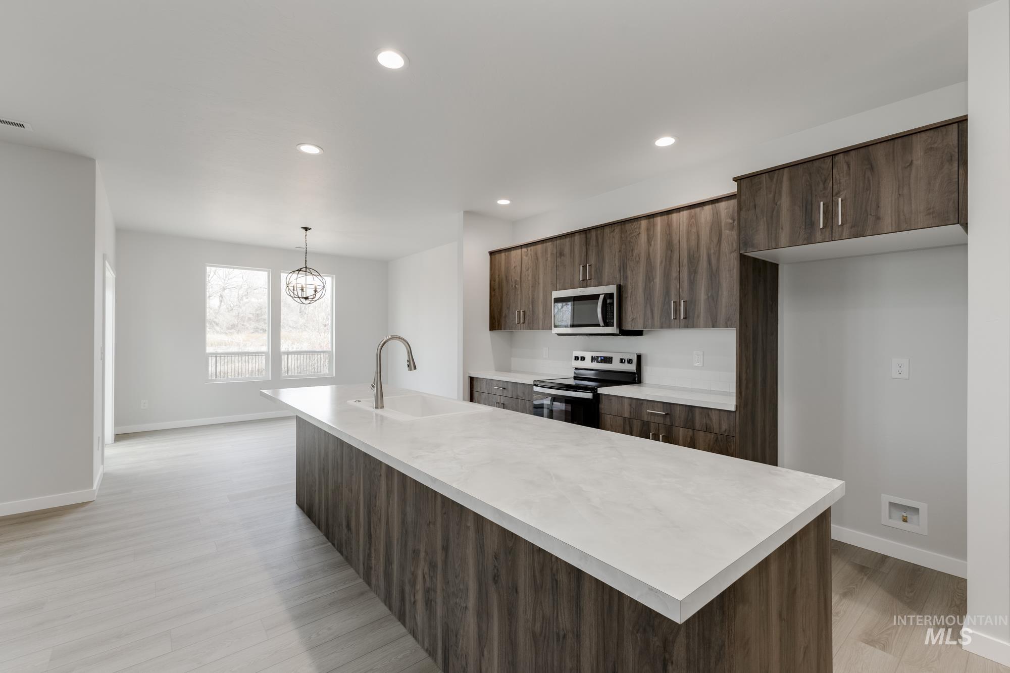 13638 Redway Court Caldwell, ID 83607 - Photo 4 of 21 Kitchen with light countertops, appliances with stainless steel finishes, a kitchen island with sink, dark brown cabinetry, and recessed lighting