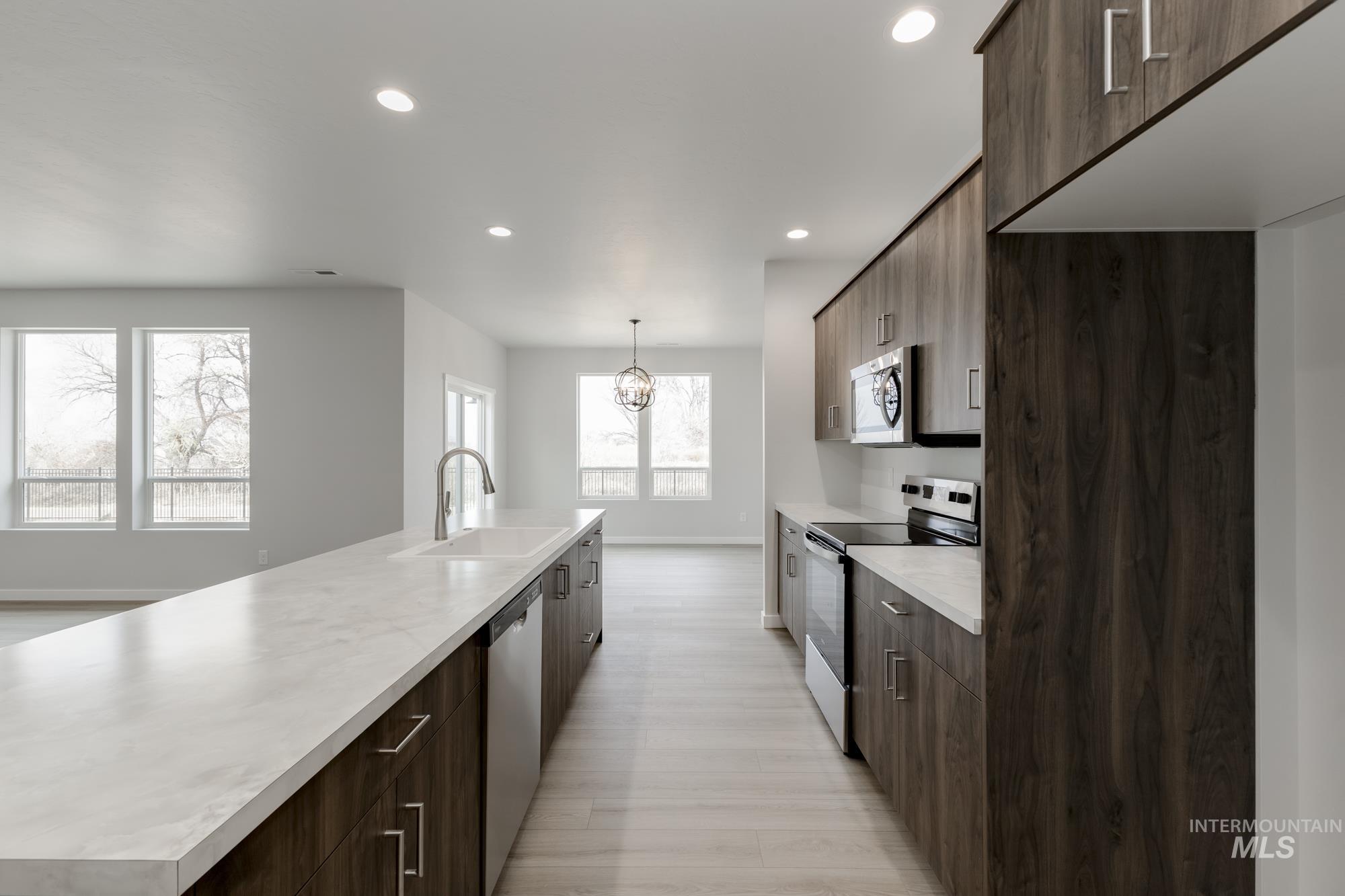 13638 Redway Court Caldwell, ID 83607 - Photo 5 of 21 Kitchen with appliances with stainless steel finishes, light countertops, dark brown cabinetry, modern cabinets, and a large island with sink