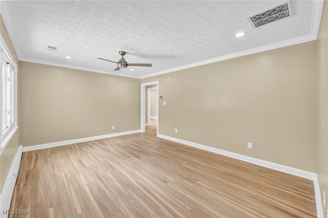 1447 East Sprague Road Independence, OH 44131 - Photo 16 of 47 Unfurnished room featuring ceiling fan, ornamental molding, light hardwood / wood-style flooring, and a textured ceiling