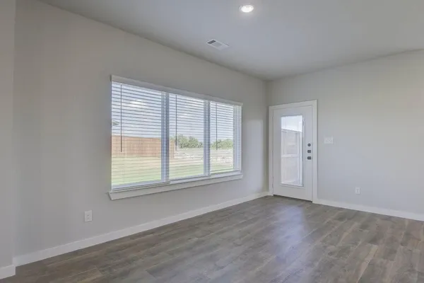 an empty room with wooden floor and windows