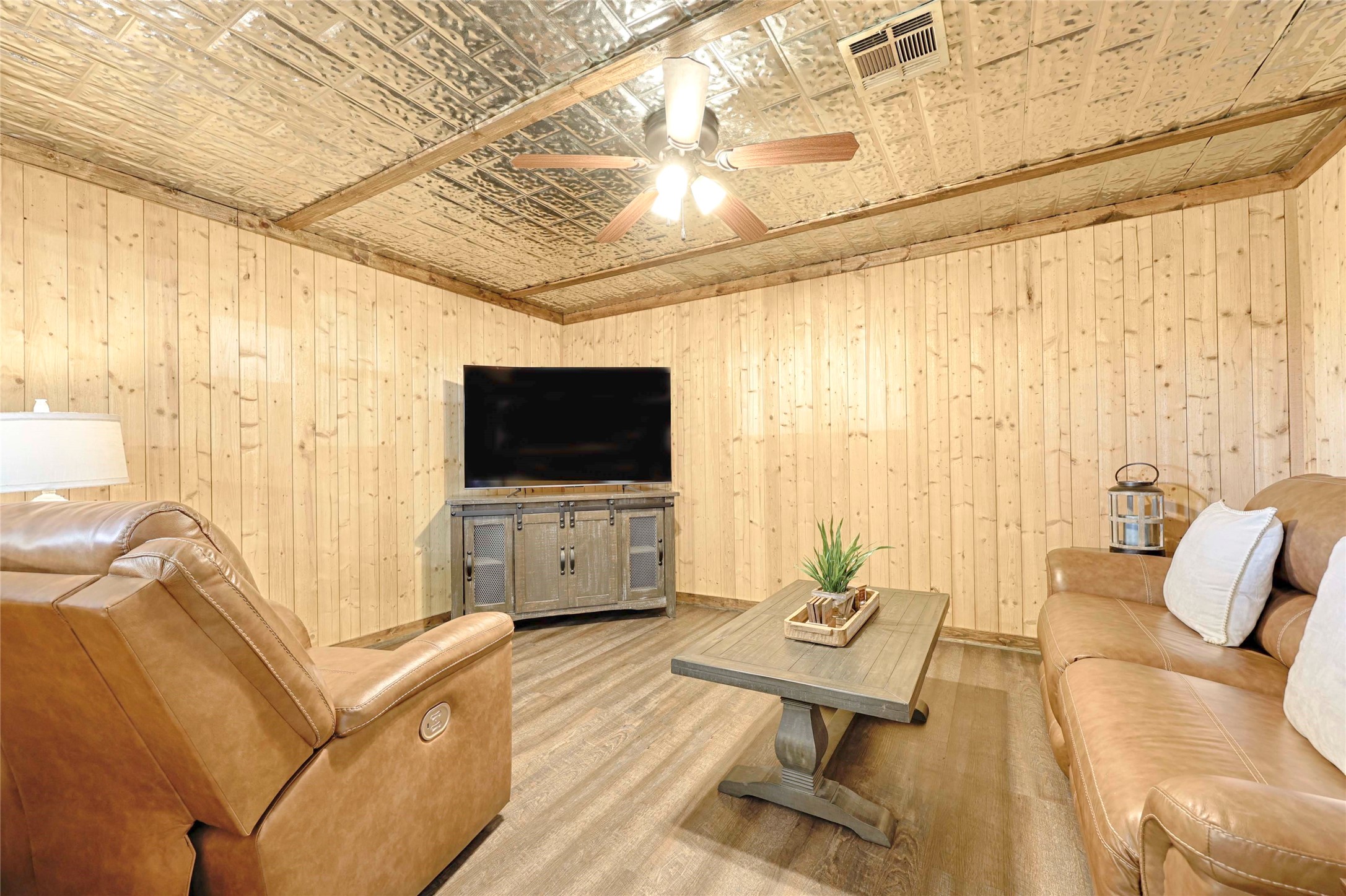 1055 County Road Weimar, TX 78962 - Photo 10 of 35 Cozy and inviting living area highlighted by warm wood walls, rustic ceiling details, and durable flooring. This comfortable space is ideal for relaxing or gathering, offering a charming lodge-style atmosphere with easy flow to the kitchen and dining areas