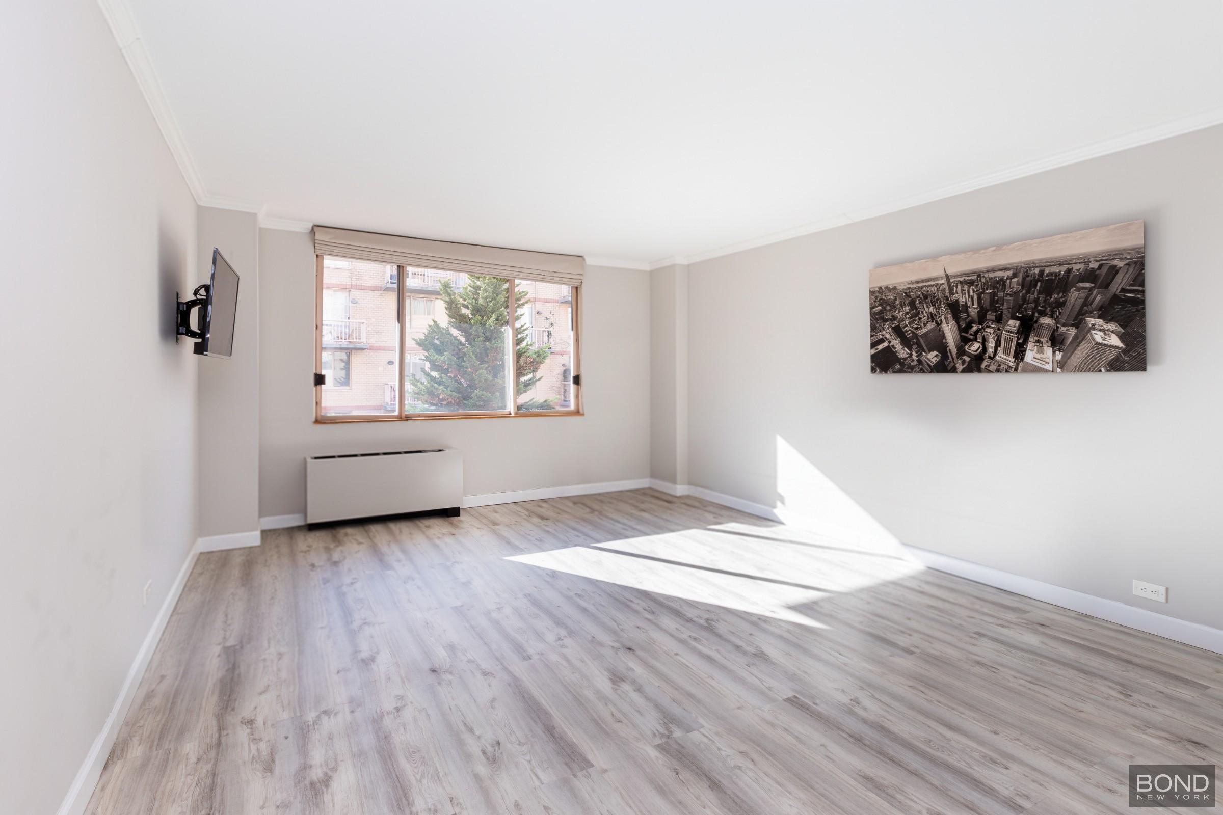 393 West 49th Street, Unit 3OO Manhattan, NY 10019 - Photo 2 of 16 a view of empty room with wooden floor and fan