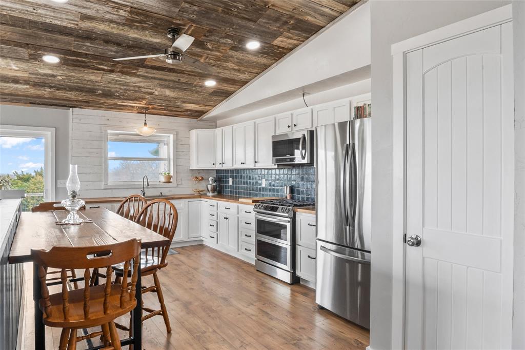 7949 North Fm 373 Road Muenster, TX 76252 - Photo 21 of 38 a kitchen with stainless steel appliances granite countertop a refrigerator a stove a sink dishwasher a dining table and chairs with wooden floor