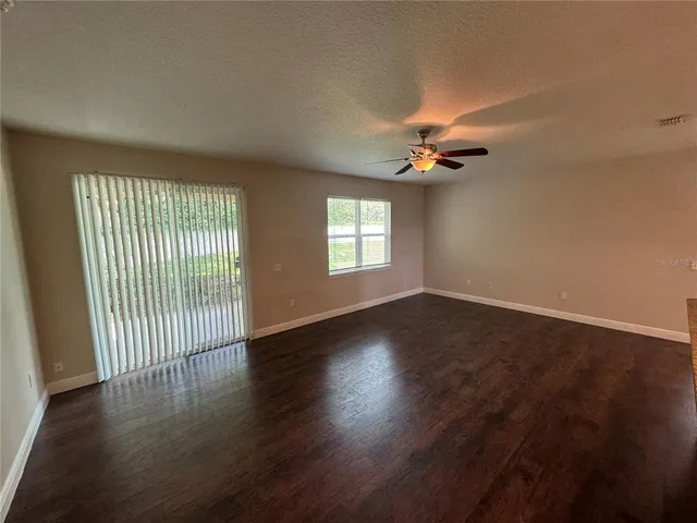 an empty room with chandelier fan and windows
