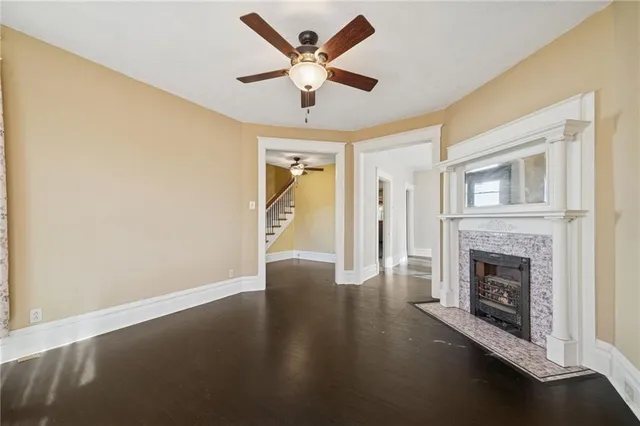 a view of an empty room with wooden floor and a fireplace