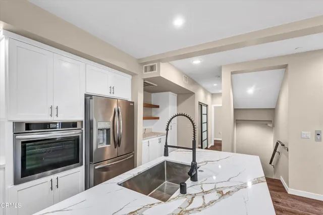 a kitchen with granite countertop a refrigerator and a stove top oven