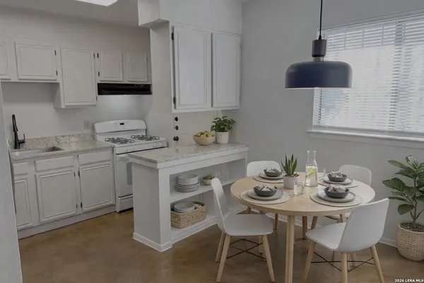 a kitchen with stainless steel appliances a white table chairs and a refrigerator
