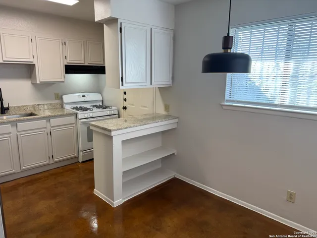 a kitchen with a stove cabinets and a window