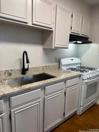 a kitchen with granite countertop white cabinets and a stove