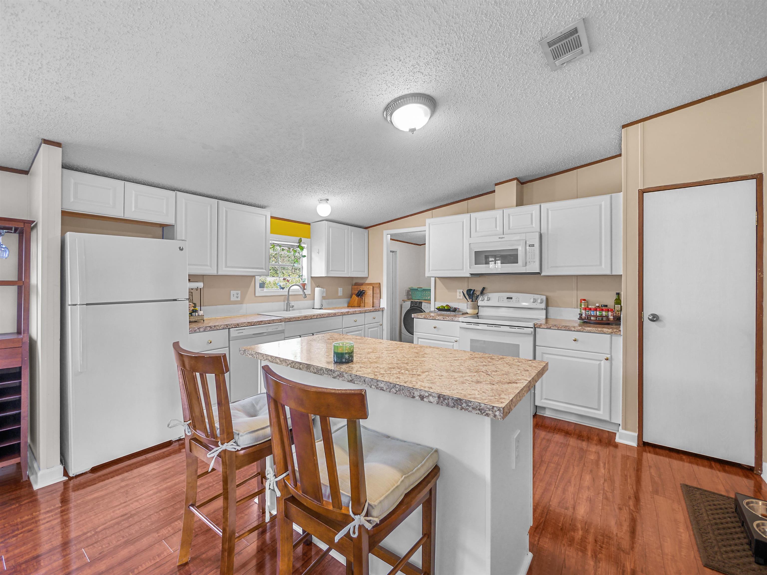 2961 Race Track Road St. Augustine, FL 32084 - Photo 9 of 42 a kitchen with stainless steel appliances granite countertop a refrigerator a stove a sink dishwasher and white cabinets with wooden floor