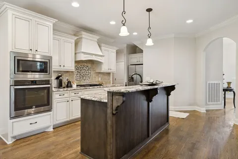 a kitchen with stainless steel appliances granite countertop a sink stove and cabinets