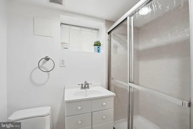 a bathroom with a shower sink vanity and toilet