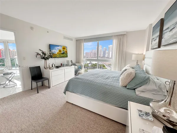 a bedroom with a bed a couch and a flat tv screen on the dresser