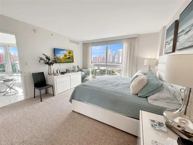 a bedroom with a bed a couch and a flat tv screen on the dresser