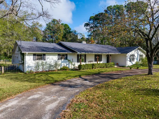 a view of an empty room with wooden floor and a kitchen