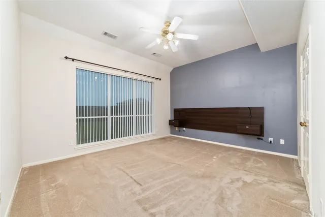 an empty room with windows and ceiling fan