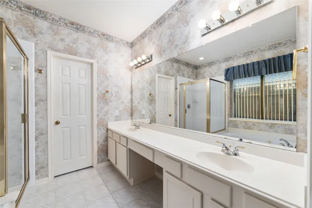 a bathroom with a sink double vanity granite tub shower and a mirror