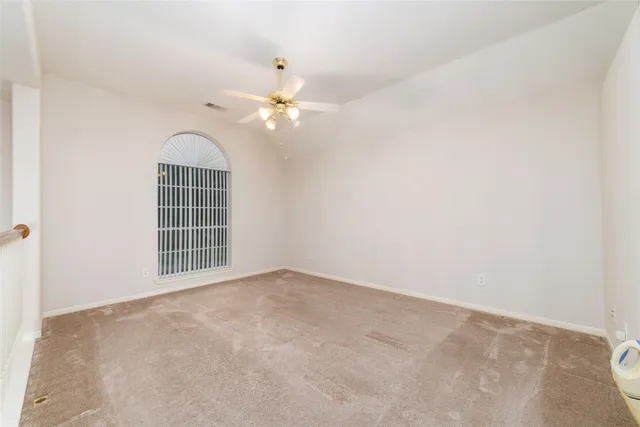 an empty room with windows and fan