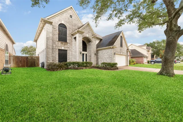 a view of a white house next to a yard with big trees
